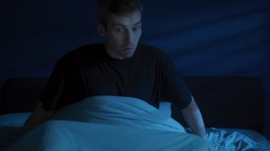 Genç adam aniden gecenin bir yarısı uykusuzluk ve kaygı ile boğuşurken, ürkmüş ve derin bir nefes alarak uykusuzluk ve endişe içinde loş mavi ışıklı yatak odasında oturuyor. Uyku bozukluğu, gece terörü