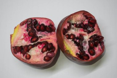 Beyaz arka planda yarı dilimlenmiş ve kırmızı nar meyvesi.