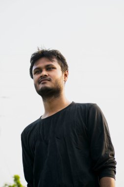 A young boy looking wearing black t-shirt in front of natural white background