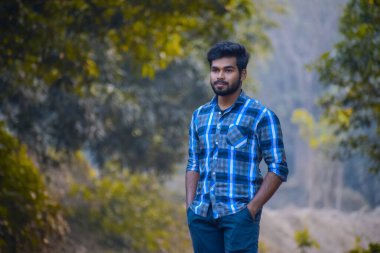 Ormanda dikilen Hintli genç bir çocuk diğer tarafa bakıyor.