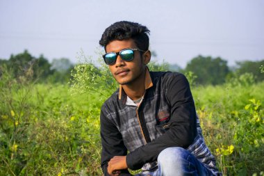 Güneşli bir günde güneş gözlüğü takan genç çocuk portresi açık havada kolsuz gömlek giyiyor.