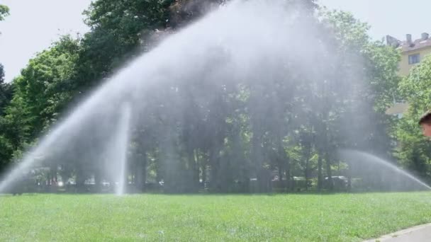 Sofia, Bulgarien - 5 juni 2021: Barn leker med vatten under varma sommardagar. Barn med trädgårdssprinkler som rinner under vattendroppar. Utomhus kul — Stockvideo
