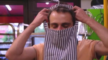 Genç gülümseyen fırıncı küçük bir kasaba fırınında duruyor ve günün başında önlük takıyor.