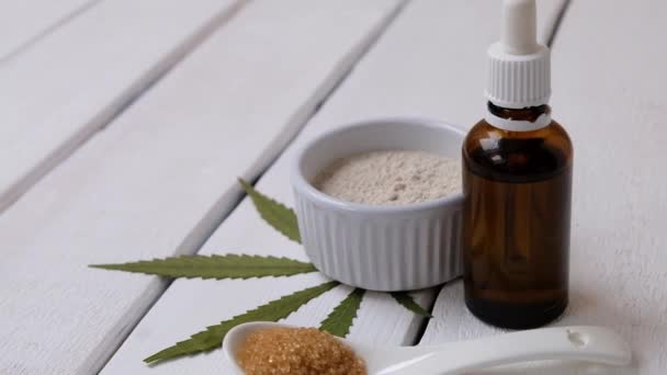 Konopí infuze produkty - marihuana mouka, cukr olej om bílé dřevěné pozadí, prostor pro text — Stock video