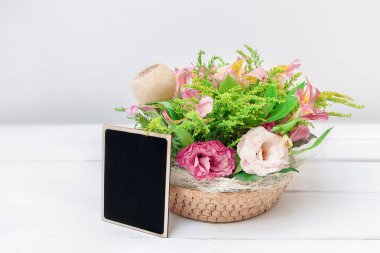 Güzel çiçekli maket ve beyaz masa arkasında siyah boş tahta.