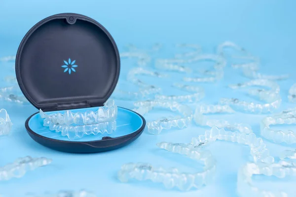 Invisible retainers case with orthodontic aligner brackets. Black plastic dental container for removable invisalign braces on blue background — Stock Photo, Image