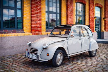 Üstü açılır gri Citroen 2cV kaldırımlı caddede ve arka planda tuğla bina
