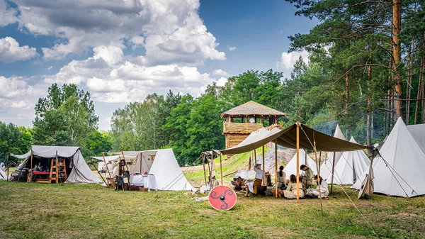 Historical reenactment of Slavic or Vikings tribe encampment with wooden palisade, fort tower and tent camp — Stock Photo, Image