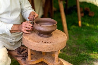 El işi çömlekçi çarkındaki çamurdan çömlek yapıyor.