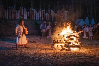 Cedynia, Polonya, Haziran 2019 'da Kupala Gecesi' nin yeniden canlandırılması Polonya 'da, tahta maskeli şaman Noc Kupaly ateşe tahıl döktü. Slav bayramı yılın en kısa gecesinde kutlandı