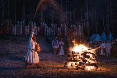 Cedynia, Polonya, Haziran 2019 'da Kupala Gecesi' nin yeniden canlandırılması Polonya 'da, tahta maskeli şaman Noc Kupaly ateşe tahıl döktü. Slav bayramı yılın en kısa gecesinde kutlandı