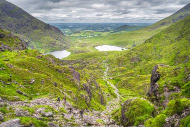 İrlanda 'nın en yüksek dağı Carrauntoohil' e ulaşmak için zorlu patika olan Şeytan Merdiveni 'ne tırmanan bir grup yürüyüşçü 2019 Temmuz' unda