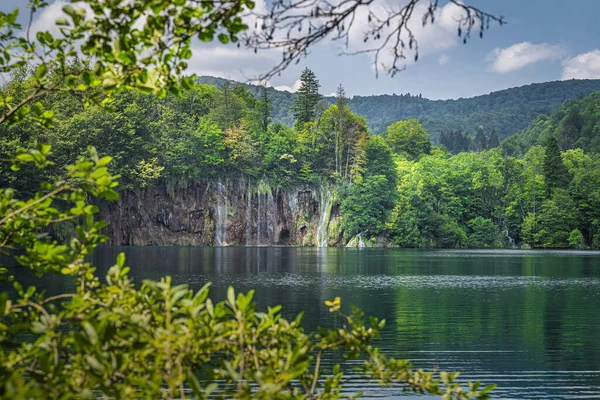 Cascadas iluminadas por la luz del sol con marco natural de ramas en los lagos de Plitvice —  Fotos de Stock