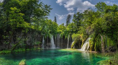 Panorama with waterfalls, water coming down from lichens to turquoise coloured lake in Plitvice Lakes clipart