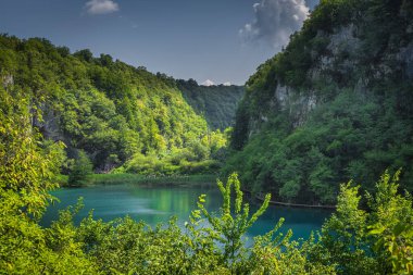 Yüksek uçurum, vadi, turkuaz renkli göl ve turistler Plitvice Gölleri, Ulusal Park UNESCO Dünya Mirası ve Hırvatistan 'da yürüyüş yapıyorlar.
