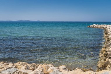 Hırvatistan 'ın Zaton körfezinde kayalık iskele ile Adriyatik Denizi' nin sakin, turkuaz bulutlu ve kristal berrak suları