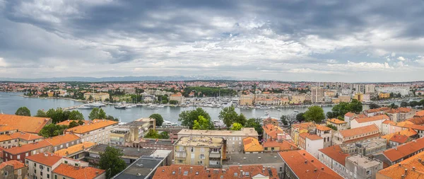 Large panorama with drone or birds eye view on orange tiled roofs and cityscape of Zadar. Bay or marina with moored yachts and boats, Croatia