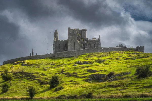 Majestic Castle, Cashel Kayası, kule etrafında uçan kargalar ve arka planda dramatik kara fırtına bulutları, County Tipperary, İrlanda