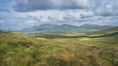Yeşil tarlaları, çiftlikleri, ormanı ve gölü olan güzel bir vadi tepeler ve dağlarla çevrili, Dingle Yarımadası, Vahşi Atlantik Yolu, Kerry, İrlanda
