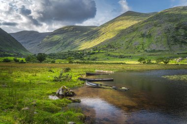 Lough Gummeenduff 'ta batık çarklı tekneler ve güzel Black Valley tepelerinde sıcak güneş ışığı, MacGillycuddys Reeks dağları, Kerry Halkası, İrlanda