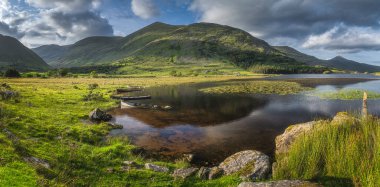 Lough Gummeenduff 'ta batık kürek tekneleri olan büyük bir panorama. Gün batımında güzel Kara Vadi, MacGillycuddys Reeks dağları, Kerry Halkası, İrlanda