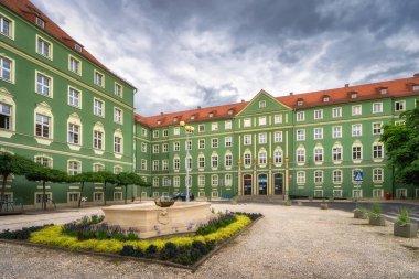 Szczecin, Poland, 5 Aug 2021 This captivating scene showcases a historic green building, Szczecin City Hall, that beautifully encircles a peaceful courtyard adorned with blossoming flower beds
