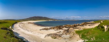 Connemara, Galway, İrlanda 'da turkuaz Dogs Bay' li Sandy Cove. Kumullar, yumuşak dalgalar solgun kumu yosun ve kayalık çıkıntılarla kaplıyor. Açık mavi gökyüzünün altındaki uzak tepeler