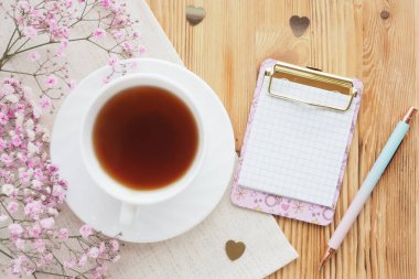 Çay fincanı, tahta arka planda klipsli ve dolma kalemli pano. Yaşam tarzı, üst görünüm