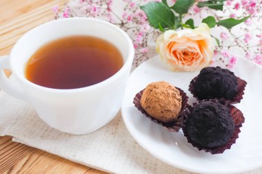 Bir fincan tabağında üç şeker, bir fincan çay ve çiçekler. Yaşam tarzı