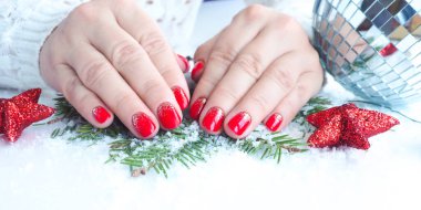 Bayrak tutan kadın elleri güzel manikür ve parlak kırmızı tırnak cilası gösteriyor. Disko topu, Noel ağacı dalları, yıldızlar ve kar beyaz bir masada.