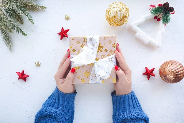 青いセーターの女性の手は白いテーブルの上にクリスマスプレゼント 星とクリスマスボールと箱を保持します 上からの眺め ライフスタイル — ストック写真