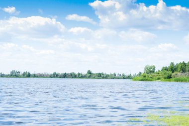 Güzel manzara koyu mavi göl, yeşil orman ve bulutlu gökyüzü