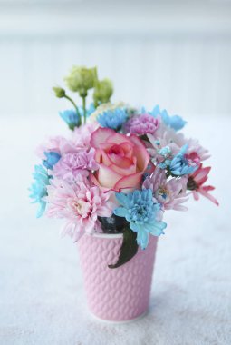 Masadaki pembe bardakta güzel bir buket çiçek.