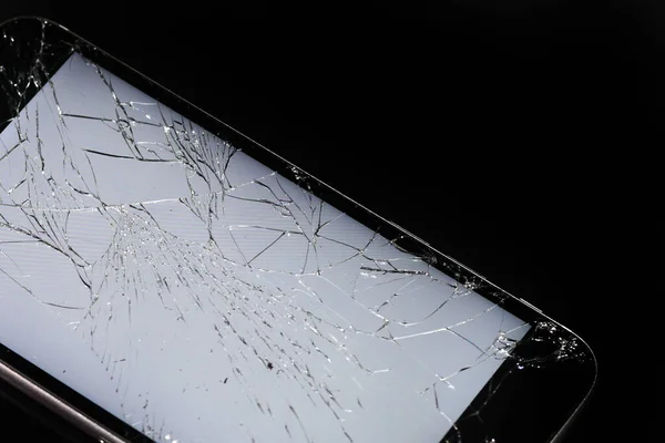 glowing broken smartphone screen close up on dark background. broken glass.
