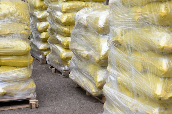 bags with building material are stacked on pallets and wrapped in stretch wrap. yellow bags.