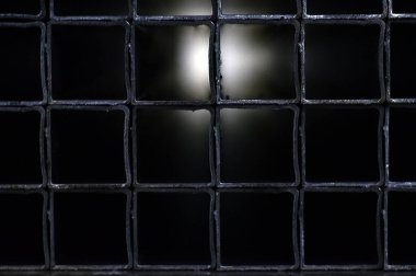 Metal ürünler deposundaki çelik profil kare bir borudan kesilmiş. Arka planda metal ızgara var. Tünelin sonunda bir ışık..