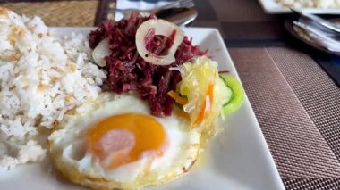 Geleneksel Filipinli kahvaltısı: sığır konservesi, sarımsaklı pirinç ve güneşli bir yumurta..