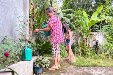 Yaşlı bir Asyalı kadın ve kızı Filipinler 'deki bahçelerini temizliyor..