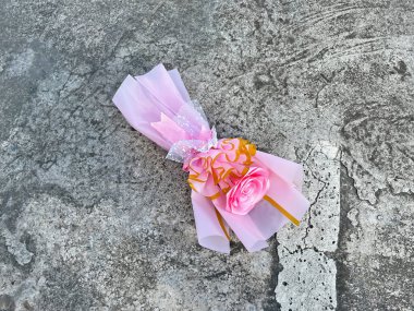Gri beton arka planda pembe el yapımı saten kurdele gül buketi.