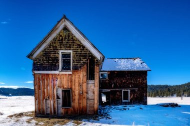 Eski terk edilmiş bir binanın etrafında kar yağıyor.