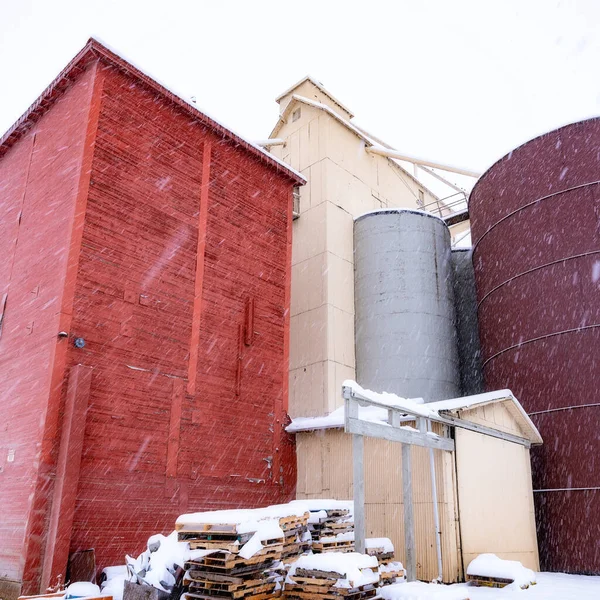 Winter cold snow falls on a farmers elevators of grain
