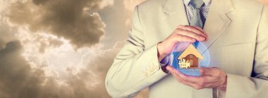 Sigorta konsepti. Emlak sigortası. Bir sigorta acentesi içinde bir evin resmi olan koruyucu bir küre tutuyor.