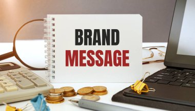 Brand MESSAGE bir not defterine, ofis aksesuarlarıyla birlikte bir ofis masasına yazılmıştır..