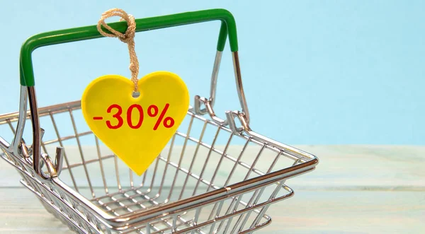 Shopping basket and heart with letters -30 percent. Sale and discount concept.