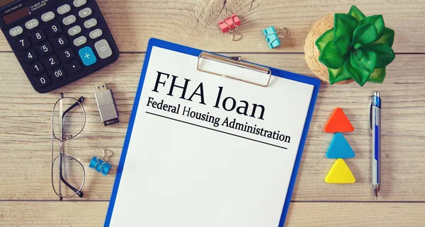 Paper with FHA loan - Federal Housing Administration on a table, calculator and glasses