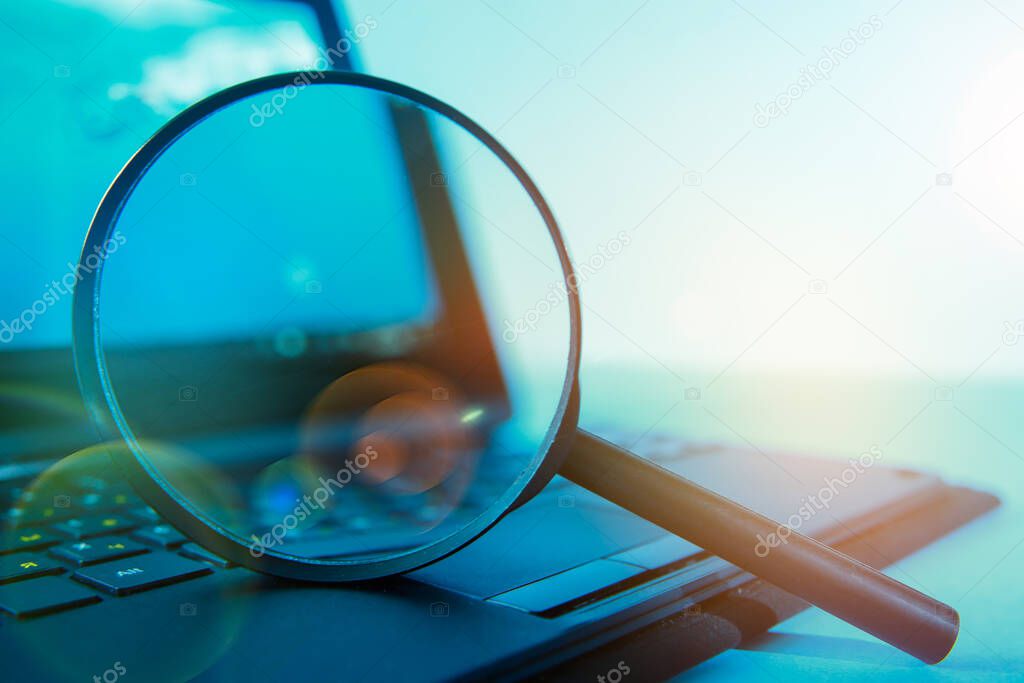 Laptop computer with magnifying glass, concept of search