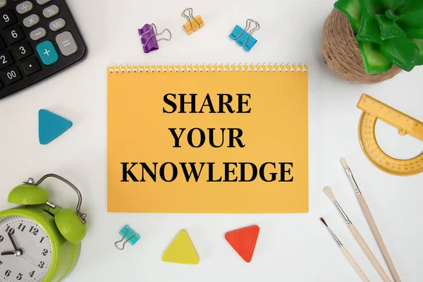 SHARE YOUR KNOWLEDGE is written on a notepad on an office desk with office accessories.