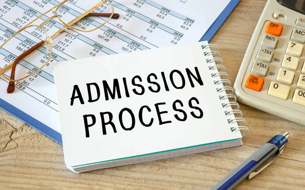 ADMISSION PROCESS is written on a notepad on an office desk with office accessories.