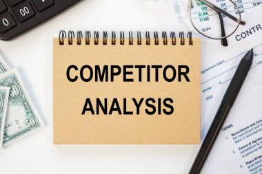Ofis masasında kırtasiye arasında COMPETITOR ANALYSIS metni bulunan defter.