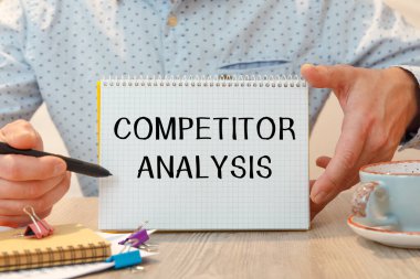 Ofis masasında kırtasiye arasında COMPETITOR ANALYSIS metni bulunan defter.